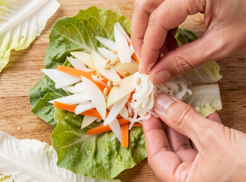 Julienned radish, carrot, slivered pear and pine nuts being stuffed between the leaves of salted napa cabbage to make white baek kimchi