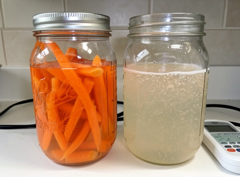 Two jars of fermenting carrots side by side, one freshly packed and one a week in with cloudy bubbling brine, a pH meter beside them