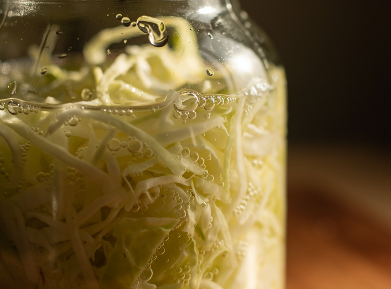 Macro view of carbon dioxide bubbles rising through cloudy sauerkraut brine during active fermentation