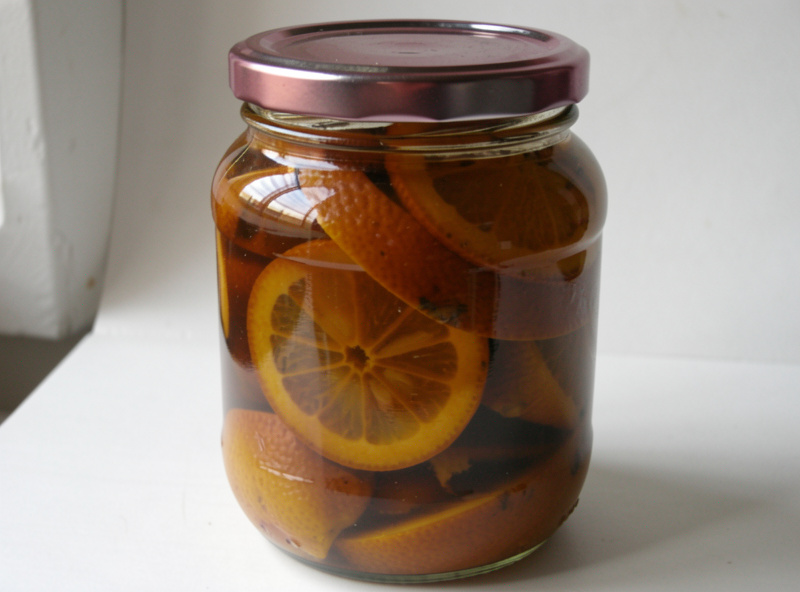 A well-aged jar of deeply cured preserved lemons with silky dark-golden rinds fully submerged