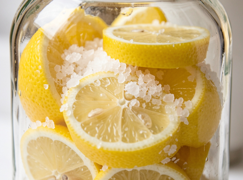 Quartered lemons packed tightly with coarse sea salt inside a clear glass jar